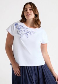 Camiseta blanca de manga corta con estampado de cachemira azul en el pecho, hecha de tela suave, con cuello redondo y un corte relajado.