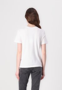 White short-sleeve T-shirt with a round neckline, made of soft cotton, featuring a smooth texture and a slightly fitted shape.