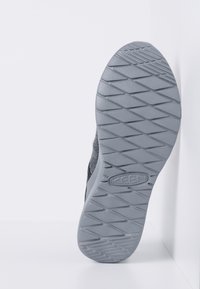 Grau gummierte Sohle mit einem strukturierten Muster, das ein Diamantprofildesign zeigt. Logo auf der flachen Oberfläche nahe der Ferse angebracht.