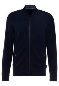 Marinblå långärmad zipjacka med ribbat krage, två framfickor med knäppning och en figursydd midja och ärmslut.