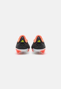 Scarpe da calcio nere e arancioni con una tomaia texturizzata, suola argento e tacchetti visibili alla base, con un logo del marchio sul tallone.