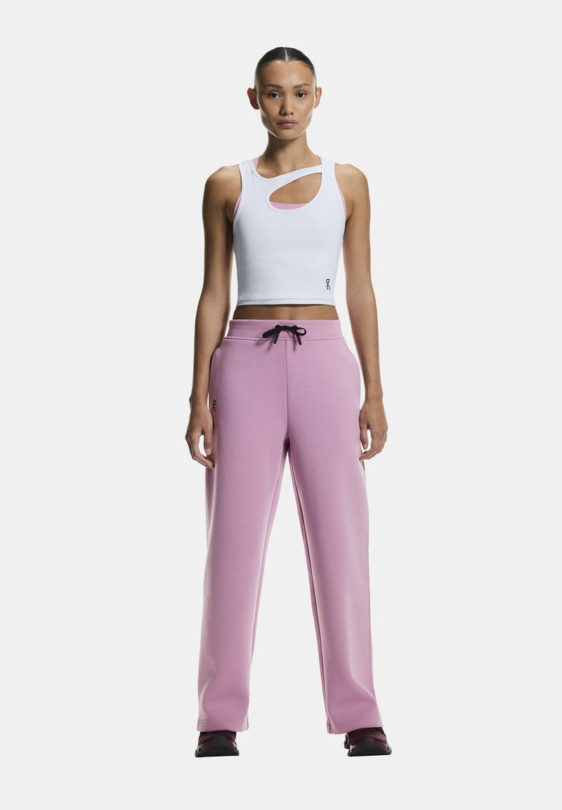 Crop top blanc avec un design découpé et des accents roses, assorti à un pantalon de survêtement rose avec un cordon de serrage ajustable et un logo.