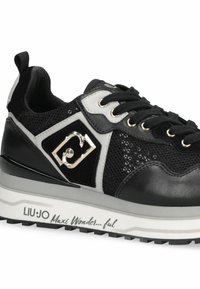 Baskets noires et grises avec dessus en mesh et cuir, présentant des accents dorés, des panneaux texturés, et une semelle blanche coussinée avec texte de marque.