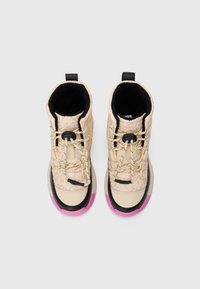 Beige High-Top-Sneaker mit pinken abstrakten Mustern, schwarzen Akzenten, schwarzen Zuglaschen und pinken Gummisohlen, von oben auf einem weißen Hintergrund gezeigt.
