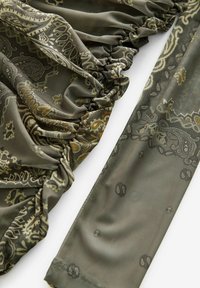 Olivovo zelená tkanina s paisley vzorom; nariasenie pozdĺž okraja vytvára textúru; hladký, ľahký materiál; obsahuje jemné detaily v svetlejších tónov.