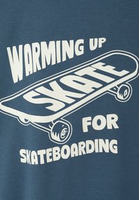 Blue sweatshirt featuring white text that reads "WARMING UP SKATE FOR SKATEBOARDING" with a graphic of a skateboard.