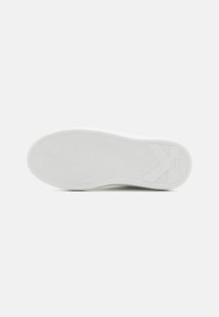 Semelle de sneaker blanche avec caoutchouc texturé. Présente une surface lisse, des motifs en vagues et des détails de logo près du talon.