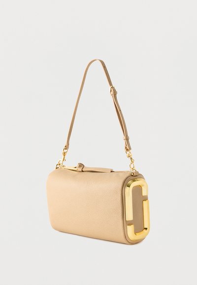 Μπεζ δερμάτινη τσάντα ώμου με ρυθμιζόμενο ιμάντα και μεγάλο χρυσό διπλό λογότυπο C στο πλάι.