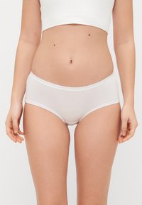 White cotton hipster panties with a smooth texture, elastic waistband, and no visible patterns, seated on a neutral background.