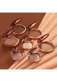 Produits de maquillage compacts dans des boîtiers en or rose avec des couvercles miroir ; varie des teintes claires aux foncées ; textures douces et détails de design élégants.