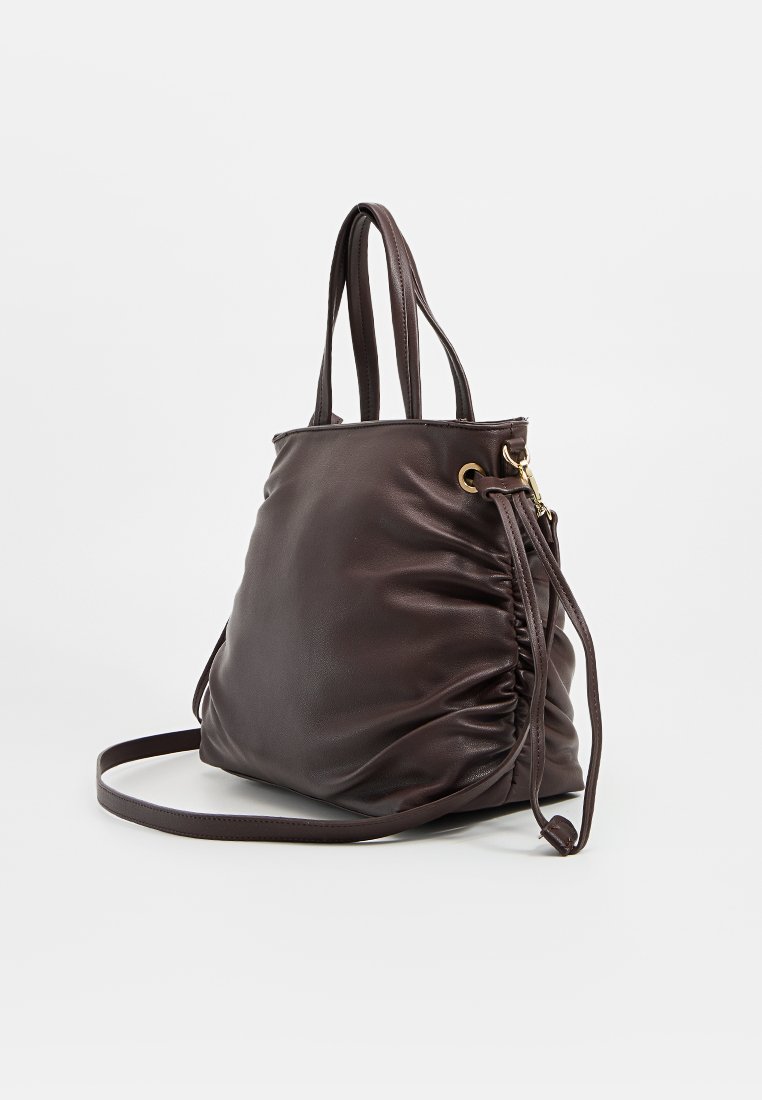 Sac en cuir marron avec un design décontracté, doté de deux poignées, d'une sangle amovible et d'accents en métal doré. Détail de surface texturé.