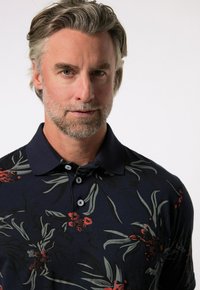 Marinblå polo skjorta med ett blommönster, grå löv och röda blommor, tre knappar och en klassisk kragsdesign.