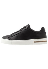 Sneaker en cuir noir avec une semelle en caoutchouc blanc, bout rond et accents texturés. Doté de lacets et d'un détail en liège sur le panneau latéral.