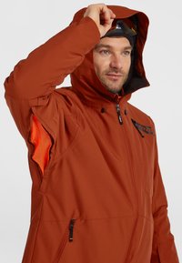 Heren oranje waterdichte jas met capuchon, rits aan de voorkant en mesh gevoerde onderarmventilatie. Kenmerkt zich door een prominent logo op de borst en zijzakken.