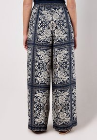 Hose mit breitem Bein in Marineblau, mit floralem und geometrischem Design in Creme. Sie verfügt über einen elastischen Bund und einen leichten Stoff.