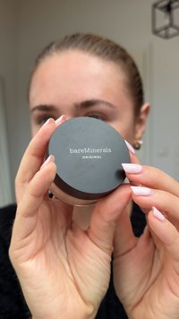 Musta pyöreä astia, jossa on kirkas pohja, merkitty "bareMinerals ORIGINAL" valkoisella tekstillä. Sujuva matta pinta ja tyylikäs muotoilu.