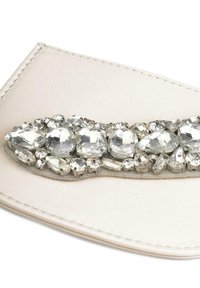 Clutch in pelle bianca caratterizzato da un'array decorativa di strass trasparenti in varie forme, che aggiungono texture e luminosità.