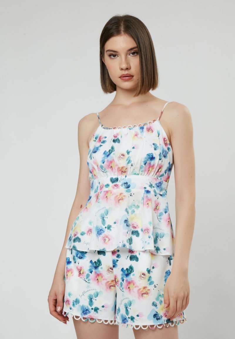 Witte bloemenpeplumtop en shorts set, met pastel bloemen, scalloped randen, spaghettibandjes en subtiele schrijfinzetten.