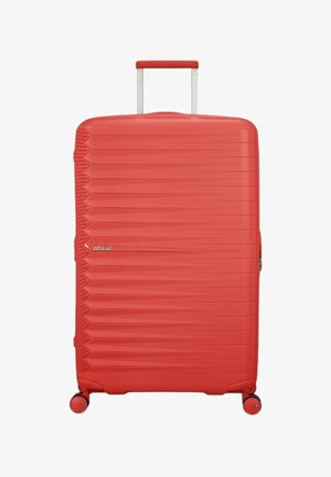 Valigia rigida rossa con un design testurizzato a strisce, manico telescopico e quattro ruote per la mobilità. Inclusi dettagli in zip argentato.