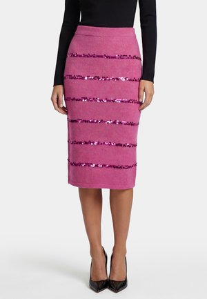 Femme portant une jupe crayon rose jusqu'aux genoux avec des bandes horizontales de sequins rose foncé et des chaussures à talons noirs.