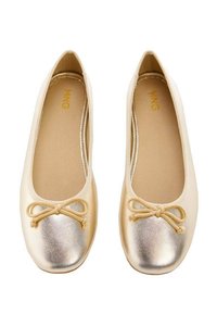 Ballerinaskor i cremefärgad tyg med en metallisk gyllenbrun tåhuvud, prydda med en rosett. Slät yta, rund form och flexibelt utförande.