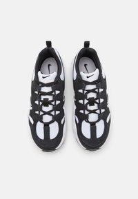 Scarpe sportive in bianco e nero con tomaia texturizzata, pannelli in mesh e lacci. Dotate di suola semi liscia e di un anello sul tallone.