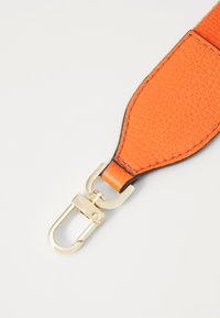 Oranžist nahast rihm tekstuuriga viimistlusega ja kuldse metallist riistvaraga. Omab klambri kinnitust lihtsaks kasutamiseks.