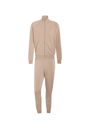 Tuta beige due pezzi con giacca con zip e collo alto e pantaloni aderenti abbinati con polsini elasticizzati.