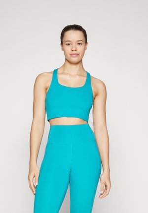 Completo sportivo turchese composto da un reggiseno sportivo corto con spalline larghe e leggings a vita alta, realizzato in un tessuto morbido ed elastico.