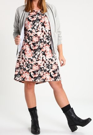 Robe fleurie avec une base noire, ornée de fleurs roses et blanches. Associée à une veste zippée gris clair et des bottes de combat noires.
