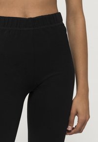 Zwarte leggings met een soepele, rekbare textuur. Beschikt over een brede elastische tailleband en een strakke pasvorm.