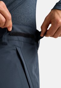 Donkerblauwe broek van een textuurstof, met een veilige klittenband tailleband, zijzakken en een strakke uitstraling.