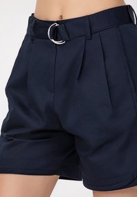 Shorts bleu marine en tissu texturé. Dotés d'une large ceinture avec une boucle en D en argent et de plis à l'avant pour une forme supplémentaire.