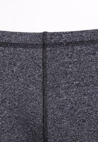 Mörkgrå träningsleggings med en texturerad yta, försedda med platta sömmar för en slät finish och en viss stretch för komfort.