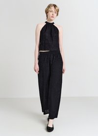 Schwarzes, bauchfreies Neckholder-Top mit strukturierter Stickerei und passenden, weit geschnittenen Hosen mit elastischem Bund und aufwendigen Mustern.