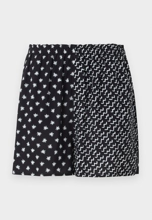 Pantaloncini neri con vita elastica con due fantasie: stelle bianche a sinistra e linee bianche a zigzag a destra.