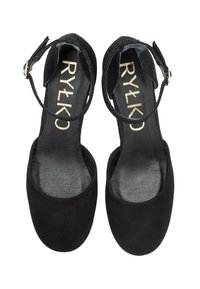 Een paar zwarte suède enkelschoenen voor dames met ronde neuzen en gouden sluitingen, van bovenaf bekeken op een witte achtergrond.