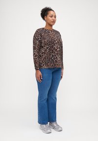 Halenka s leopardím potiskem, dlouhý rukáv, volný střih; v kombinaci s modrými přímými džíny a stříbrnými teniskami. Jednoduchý design s různými vzory.