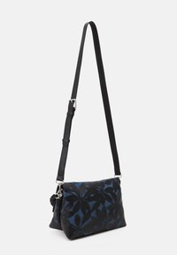 Schwarz-blau gemusterte Umhängetasche mit strukturierter Oberfläche, verstellbarem Schulterriemen und silbernen Hardware-Accents. Abmessungen nicht angegeben.