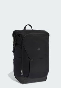 Zaino nero in nylon strutturato, dotato di manico superiore, tasca frontale con cerniera e logo discreto. Forma rettangolare con spallacci regolabili.