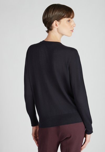 Pull marin en tissu doux, doté de manches longues et d'un ourlet côtelé. Présenté avec une coupe décontractée et un design minimal.