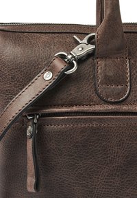 Nahaufnahme einer braunen Lederhandtasche mit einer strukturierten Oberfläche, silbernen Beschlägen und einer Reißverschlusstasche mit einer robusten Riemenbefestigung.