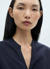 Top v-neck bleumarin, realizat dintr-un material neted, cu un design minimalist, guler drept și o croială lejeră. Linii curate și fără hardware vizibil.