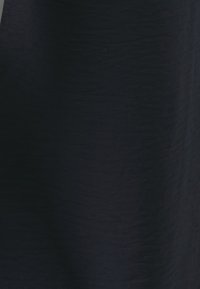 Tessuto blu navy con una trama liscia, caratterizzato da sottili variazioni nel motivo e nella luce. Nessun abbellimento o hardware evidente.