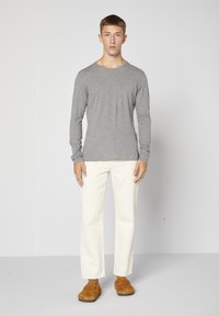 Grå långärmad skjorta, krämfärgade raka byxor, bruna mockaskor. Enkel design, avslappnad passform, mjuk textur, minimalisitsk stil.