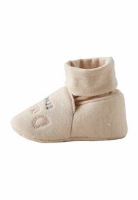 Soft beige baby bootie with fold-over ankle cuff and embroidered letters on the toe, made of quilted fabric.