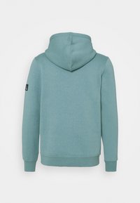 Hooded sweatshirt in a light teal color, made of soft material. Features ribbed cuffs and hem, with a tag on the left sleeve. Simple design.