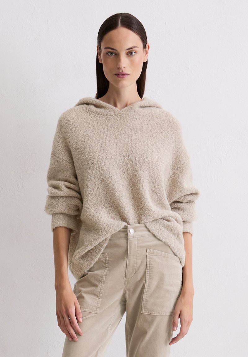 Felpa fuzzy beige con vestibilità ampia e coulisse, abbinata a pantaloni cargo beige chiaro con tasche laterali.