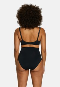 Ensemble de bikini noir comprenant un bas taille haute et un haut style bralette. Texture lisse, bretelles réglables et détails festonnés subtils.