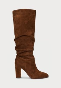 Stivale in suede marrone, alto fino al ginocchio, con un design svasato, punta affilata e tacco spesso. Dettaglio di cuciture sottili lungo le cuciture.